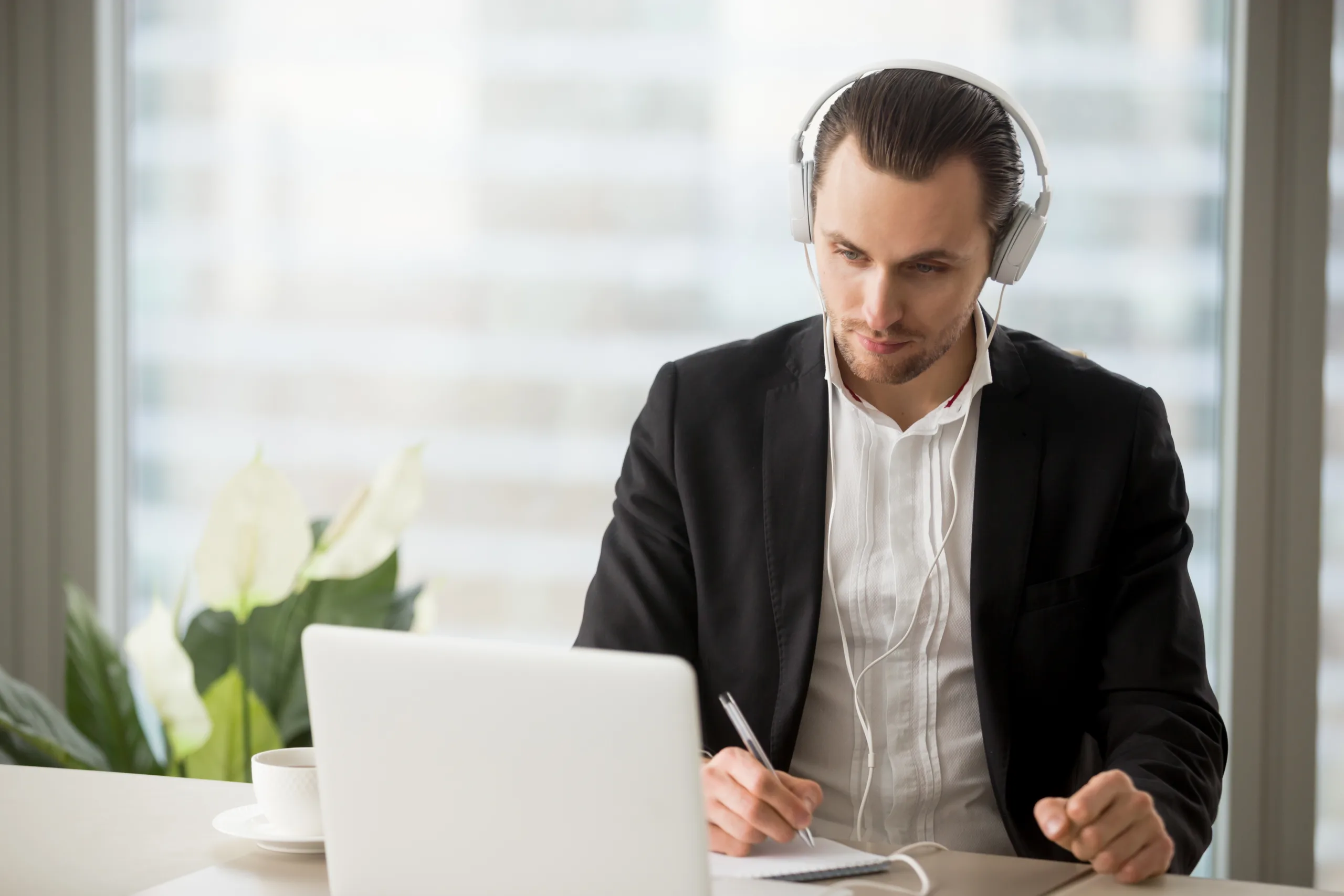Thoughtful,Businessman,In,Headphones,Taking,Notes,In,Front,Of,Laptop Diplomacy_3